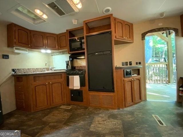 kitchen with dark tile patterned floors, black appliances, and sink