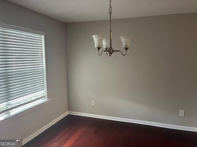 unfurnished dining area featuring a notable chandelier, a healthy amount of sunlight, and hardwood / wood-style flooring