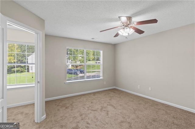 unfurnished room with light carpet, ceiling fan, a wealth of natural light, and a textured ceiling