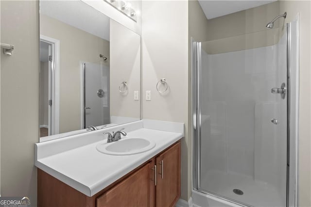 bathroom featuring a shower with shower door and vanity