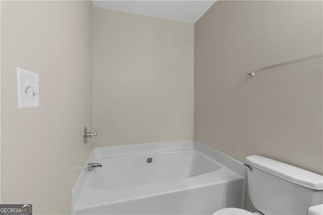 bathroom with a bathing tub, toilet, and a textured ceiling