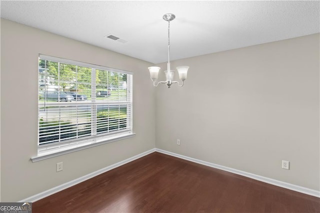 spare room with hardwood / wood-style flooring and a chandelier