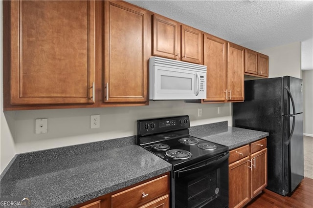 kitchen with dark hardwood / wood-style floors, black appliances, and a textured ceiling