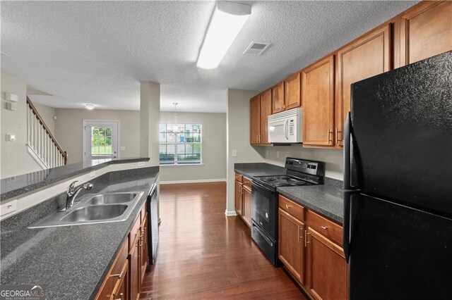 kitchen featuring decorative light fixtures, black appliances, sink, dark hardwood / wood-style floors, and a textured ceiling