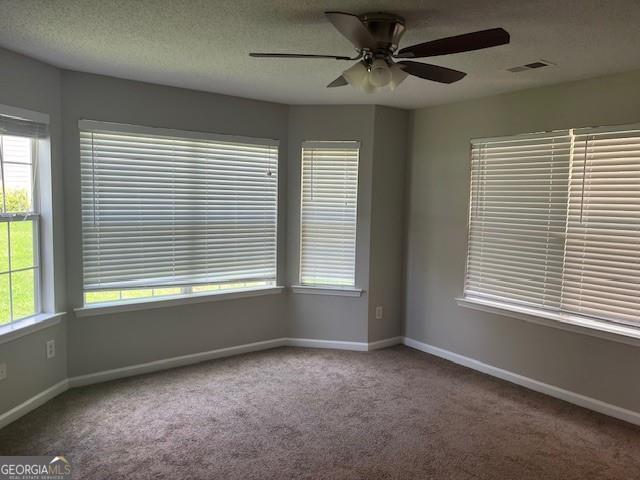 carpeted spare room with a textured ceiling and ceiling fan