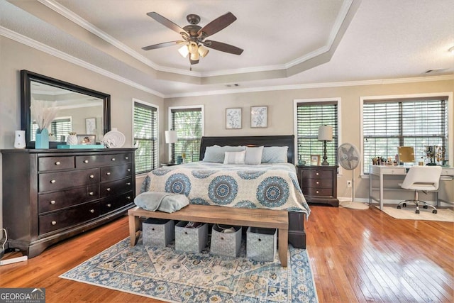 bedroom with crown molding, ceiling fan, a tray ceiling, and light hardwood / wood-style floors