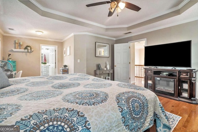 bedroom featuring ceiling fan, ornamental molding, hardwood / wood-style floors, and a tray ceiling