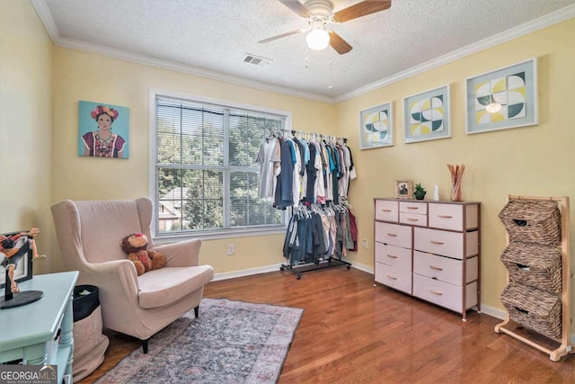 living area featuring a textured ceiling, ceiling fan, ornamental molding, and hardwood / wood-style floors