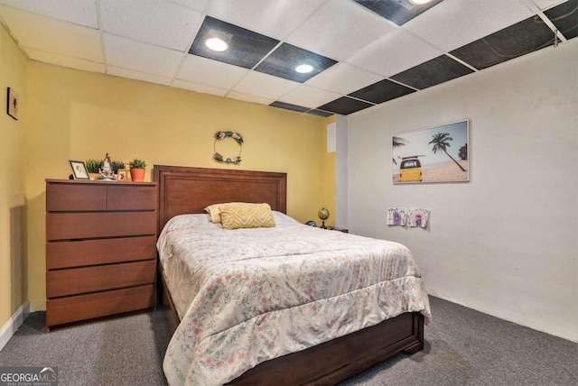 bedroom with dark colored carpet and a drop ceiling