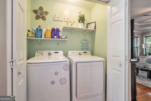 laundry area featuring ornamental molding, a textured ceiling, hardwood / wood-style flooring, and independent washer and dryer