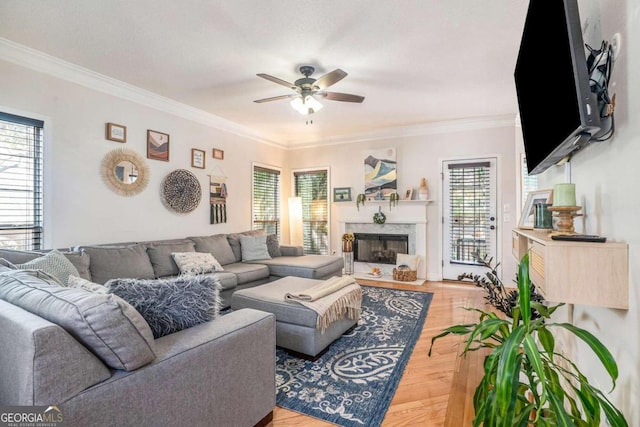 living room featuring a high end fireplace, crown molding, hardwood / wood-style flooring, and ceiling fan