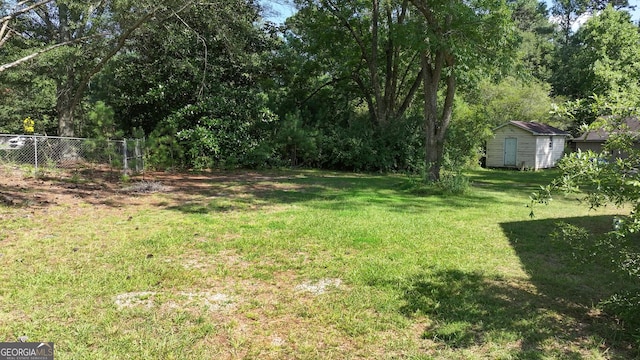 view of yard featuring fence, a storage unit, and an outbuilding