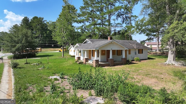 rear view of property featuring a porch and a lawn