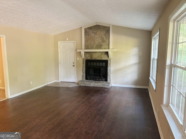 unfurnished living room featuring lofted ceiling, dark wood-type flooring, a textured ceiling, and a fireplace