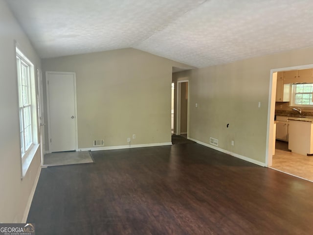 unfurnished living room featuring lofted ceiling, wood-type flooring, and a textured ceiling