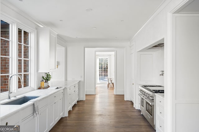 kitchen with dark wood-type flooring, sink, range with two ovens, and white cabinetry