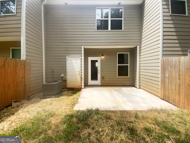 view of exterior entry with central AC and a patio