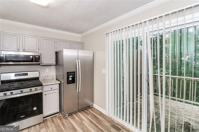 kitchen with crown molding, appliances with stainless steel finishes, a textured ceiling, and light hardwood / wood-style floors