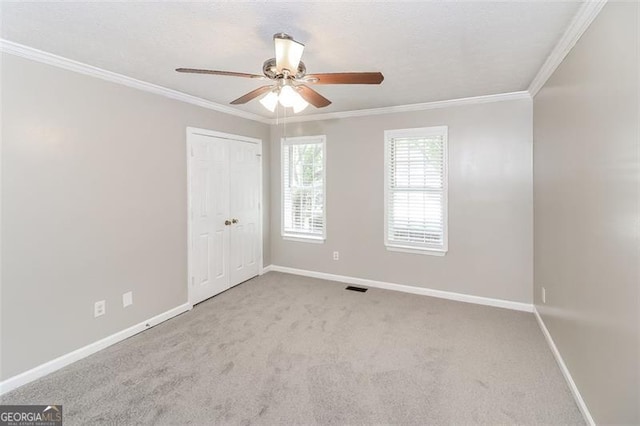 unfurnished room featuring ornamental molding, light colored carpet, and ceiling fan