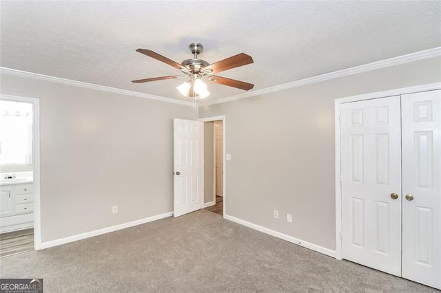 unfurnished bedroom with connected bathroom, crown molding, light carpet, a textured ceiling, and a closet