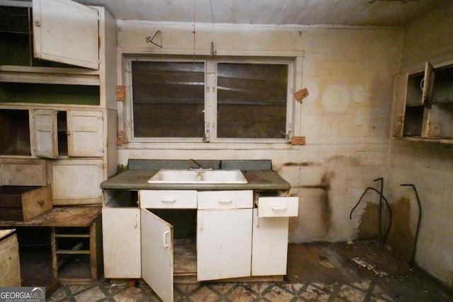 kitchen featuring dark tile patterned floors, sink, and white cabinetry