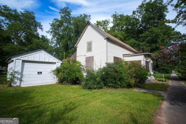 view of home's exterior with a garage, a lawn, and an outdoor structure