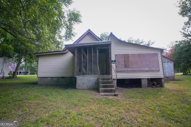 back of property featuring a sunroom and a lawn