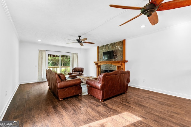 living room with a stone fireplace, dark hardwood / wood-style flooring, ornamental molding, ceiling fan, and a textured ceiling