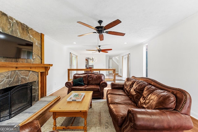 living room with hardwood / wood-style flooring, ornamental molding, a fireplace, and a textured ceiling