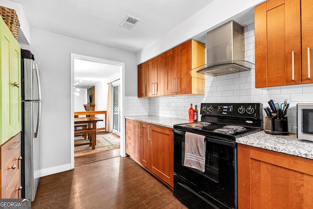 kitchen with wall chimney range hood, dark hardwood / wood-style floors, stainless steel appliances, light stone countertops, and backsplash