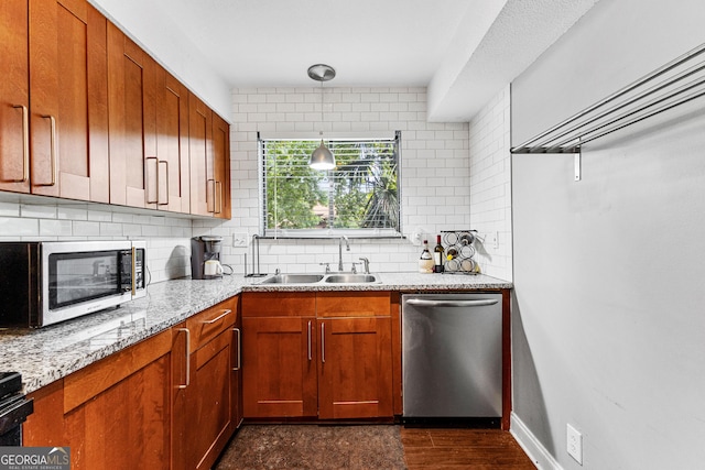 kitchen with sink, light stone counters, tasteful backsplash, hanging light fixtures, and stainless steel appliances