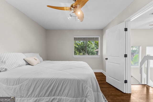 bedroom featuring multiple windows, dark wood-type flooring, and ceiling fan