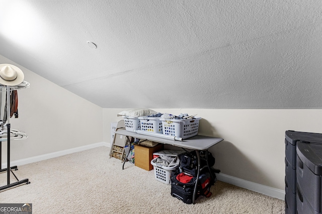 bonus room with carpet flooring, vaulted ceiling, washer and dryer, and a textured ceiling