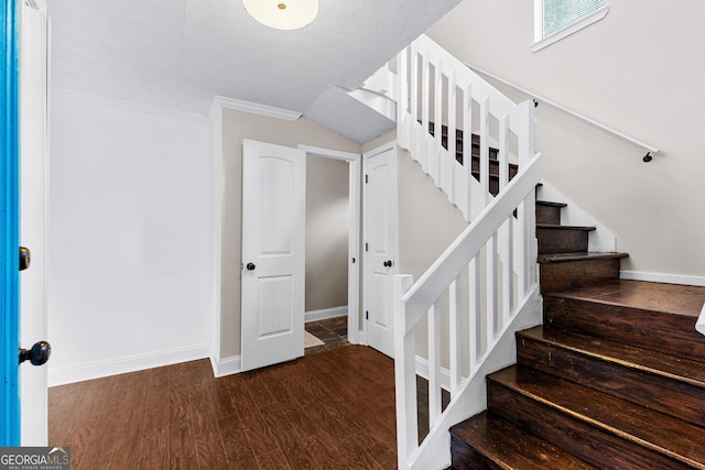 stairway with crown molding, hardwood / wood-style floors, and a textured ceiling