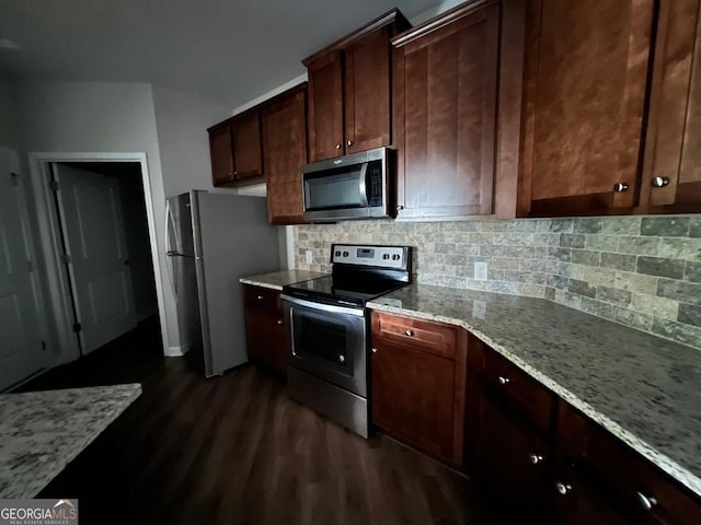 kitchen featuring tasteful backsplash, dark wood-type flooring, light stone counters, appliances with stainless steel finishes, and dark brown cabinetry