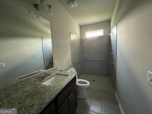 bathroom featuring tile patterned flooring, toilet, vanity, and tiled shower