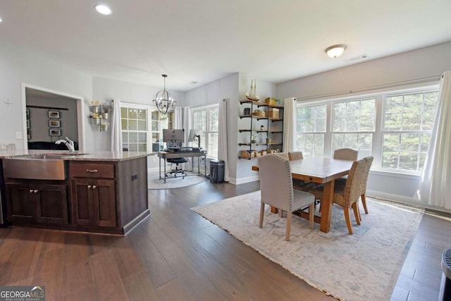 dining area featuring an inviting chandelier, sink, and dark hardwood / wood-style flooring