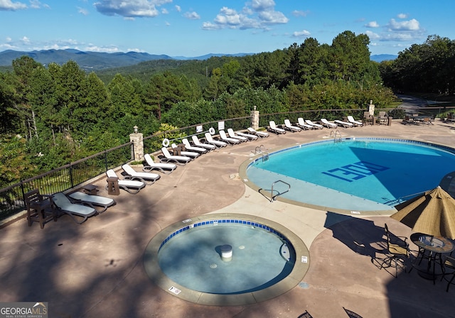 view of swimming pool with a patio, a mountain view, and a hot tub