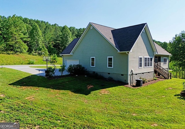 view of side of property featuring a garage, a yard, and central AC unit