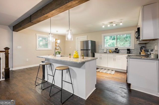 kitchen with white cabinets, dark hardwood / wood-style flooring, appliances with stainless steel finishes, and a kitchen island