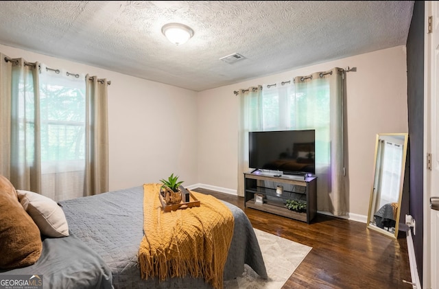 bedroom featuring multiple windows, a textured ceiling, and hardwood / wood-style floors