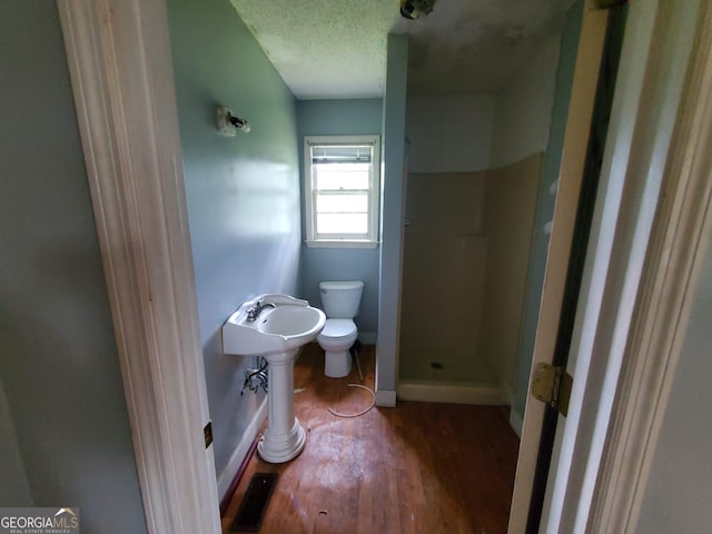 1217 Whispering Pines Rd, Albany, GA 31707 - bathroom with walk in shower, toilet, hardwood / wood-style floors, and a textured ceiling