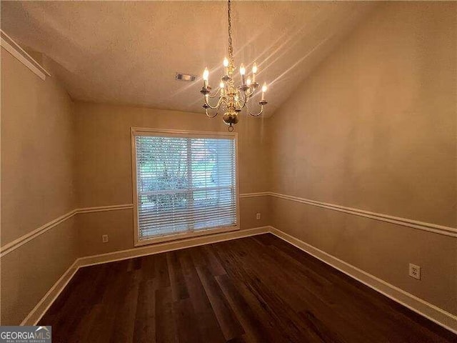 unfurnished dining area with hardwood / wood-style floors, a textured ceiling, vaulted ceiling, and a chandelier