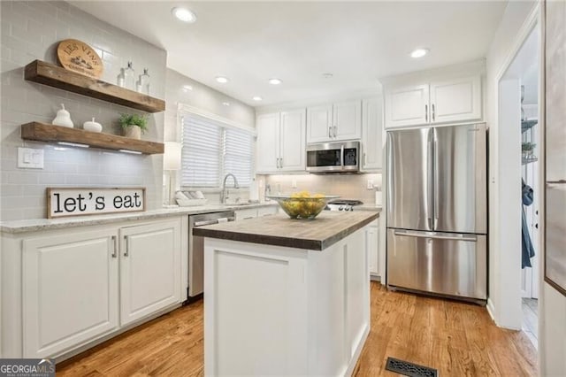 kitchen featuring white cabinetry, appliances with stainless steel finishes, tasteful backsplash, and light hardwood / wood-style flooring