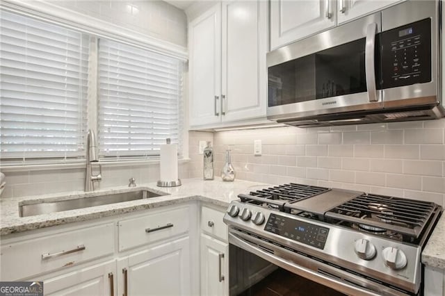 kitchen featuring sink, stainless steel appliances, tasteful backsplash, and white cabinets