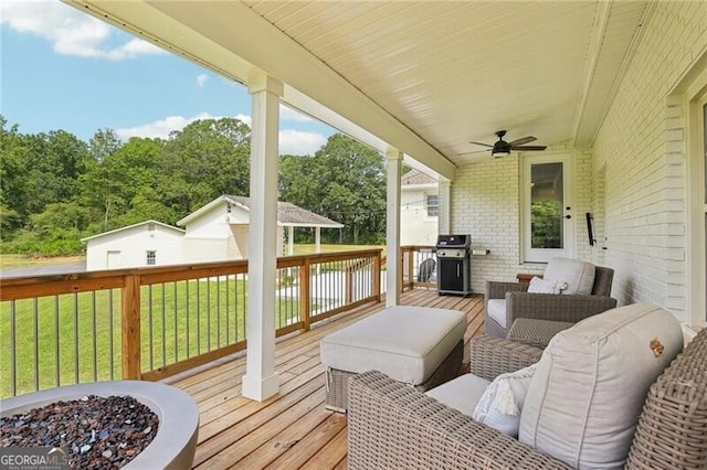 wooden deck featuring a lawn, an outdoor living space, ceiling fan, and grilling area