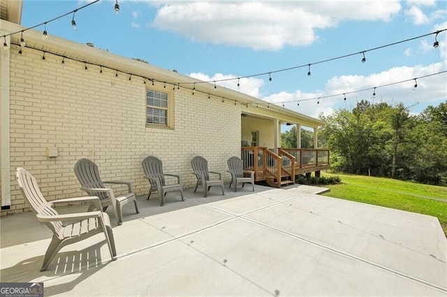 rear view of house featuring a patio, a wooden deck, and a lawn