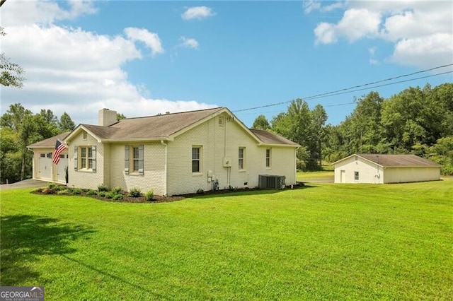 rear view of house featuring a garage, cooling unit, and a lawn