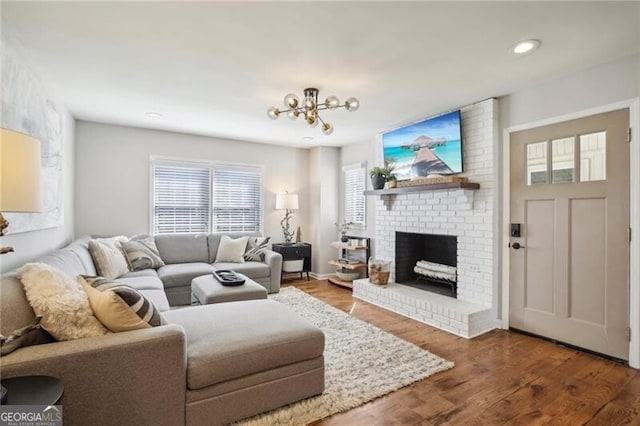 living room featuring wood-type flooring, brick wall, and a brick fireplace