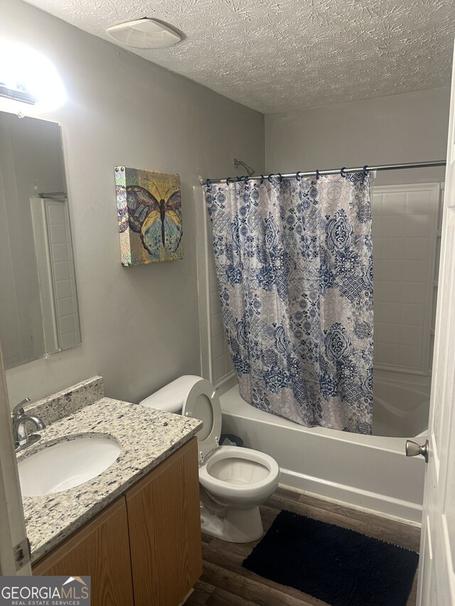 full bathroom with shower / bathtub combination with curtain, a textured ceiling, toilet, vanity, and hardwood / wood-style flooring